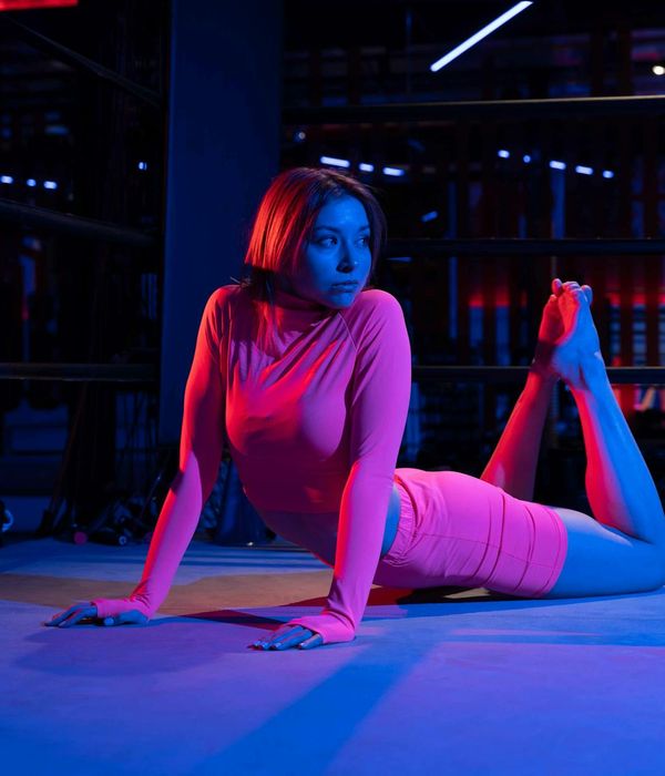 Woman in a graceful yoga pose with neon pink accents.